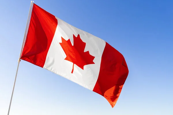 Vlag van Canada zwaaiend tegen blauwe lucht — Stockfoto