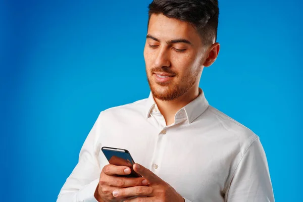 Beyaz gömlekli genç adam akıllı telefonunu kullanıyor. — Stok fotoğraf