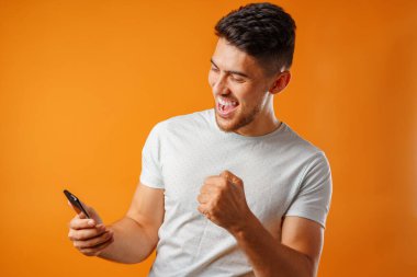 Beyaz gömlekli genç adam akıllı telefonunu kullanıyor.