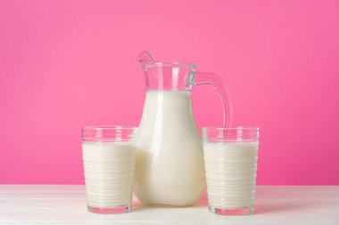 Pembe pastel arka planda taze sütle kaplı cam eşyalar.