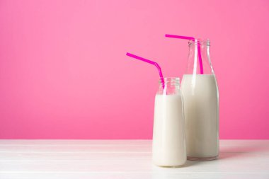 Pembe arka planda iki bardak süt ya da milkshake.