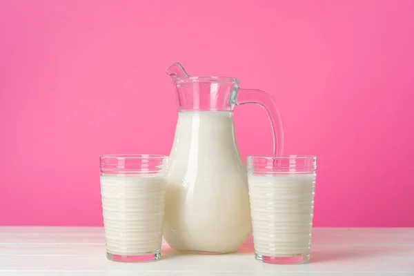 Artículos de vidrio con leche fresca sobre fondo pastel rosa — Foto de Stock