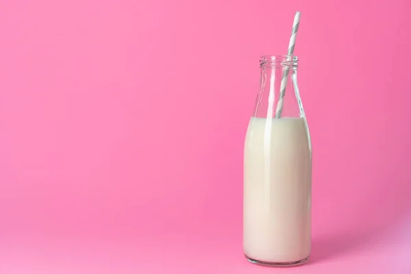 Glass bottle of milk against pink background — Stock Photo, Image