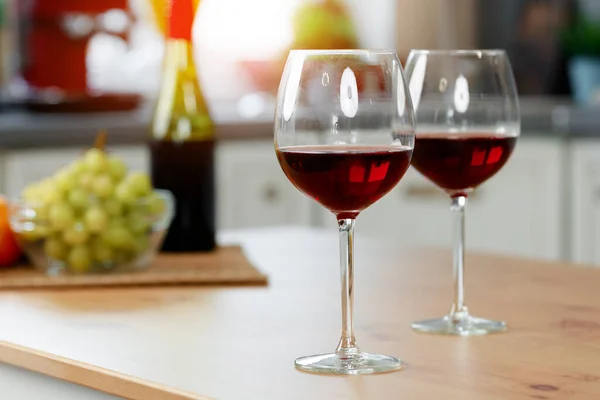 Dwa kieliszki wina z czerwonym winem na drewnianej blacie kuchennej — Zdjęcie stockowe