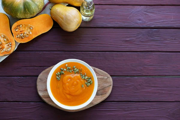 Top view of pureed pumpkin soup in a white bowl on dark table — Stock Photo, Image