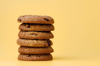 Sarı arka planda çikolata parçacıklı kurabiye yığını