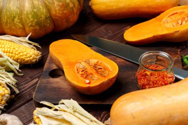 Küçük balkabağı, tahta kesme tahtasında bıçakla ikiye bölünmüş.