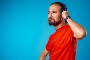 Yakışıklı orta yaşlı adam mavi kulaklıklı müzik dinliyor.
