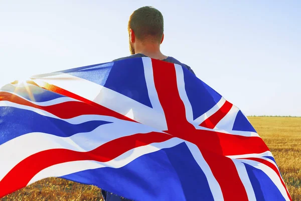 Человек с флагом Великобритании стоит в поле — стоковое фото