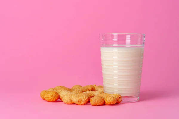Non-dairy vegan milk made of nuts in glassware against pink background