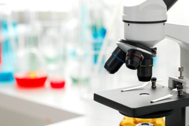 Laboratuvarda cam eşyalar ve mikroskop var.