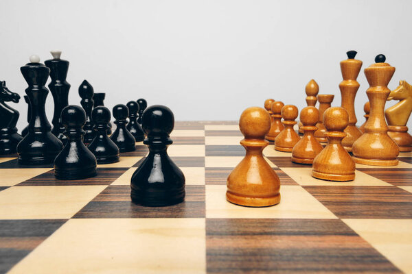 Chessboard with wooden figures against grey background