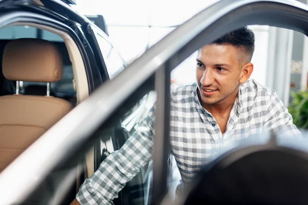 Neşeli genç adam bir galeriden yeni bir araba alıyor.