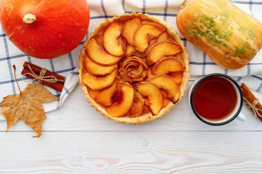 Elmalı tart masada, kabaklı ve kuru yapraklı.