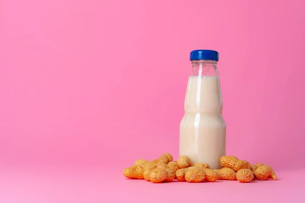 Non-dairy vegan milk made of nuts in glassware against pink background