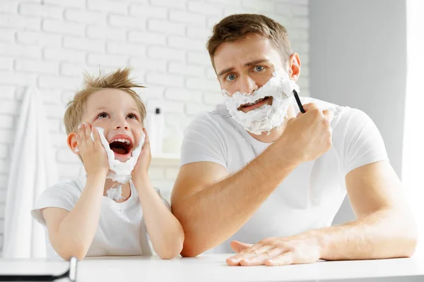 Father and little son having fun with shaving foam