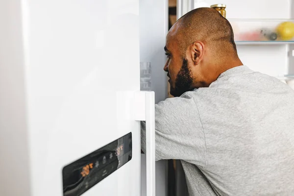 Hombre afroamericano tomando comida de una nevera en su casa — Foto de Stock