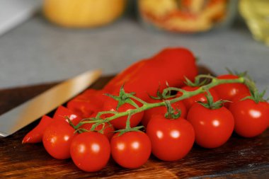 Mutfak tezgahında kiraz domatesli ahşap kesim tahtası ve biber.