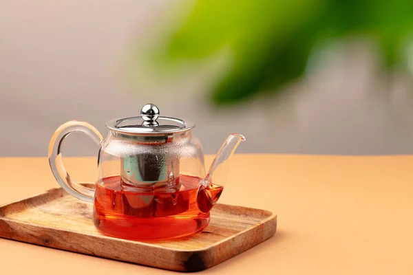 Glass teapot with black tea on background of blurred foliage — Stock Photo, Image