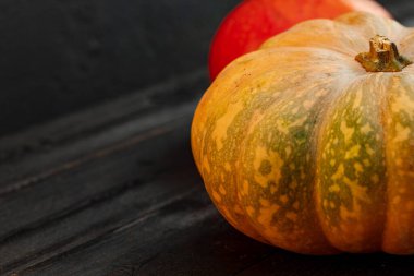 Siyah ahşap arka planda iki turuncu balkabağı