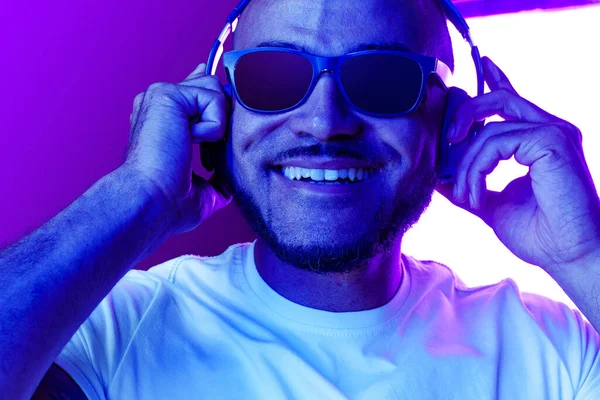 Retrato del hombre afroamericano escuchando música en luz de neón — Foto de Stock