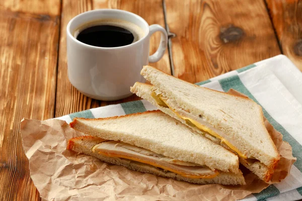 Toasted sandwich in craft paper with cup of coffee on table — Stock Photo, Image