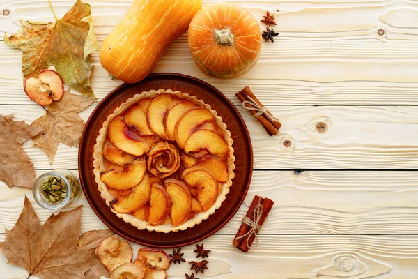 Elmalı tart masada, kabaklı ve kuru yapraklı.