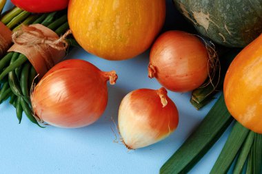 Mavi arka planda balkabağı, soğan ve biber yığını