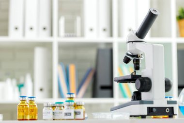 Bilim laboratuarında aşı şişeleri ve mikroskop.