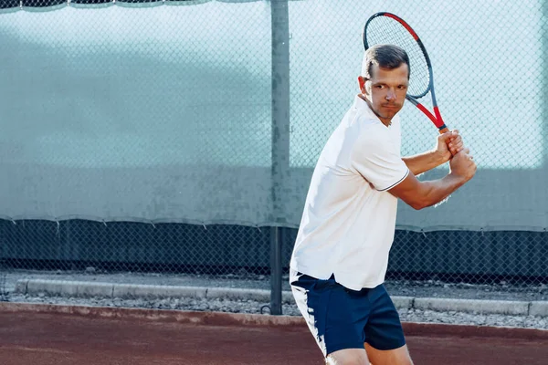 Giovane uomo gioca a tennis all'aperto sul campo da tennis al mattino — Foto Stock