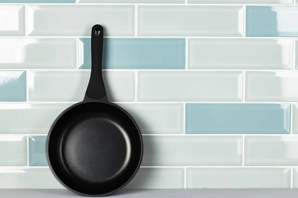 Novos utensílios de cozinha preto contra a parede azulejo azul — Fotografia de Stock