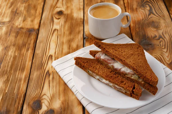 Toast kanapka i filiżanka kawy na serwetce na drewnianym stole — Zdjęcie stockowe
