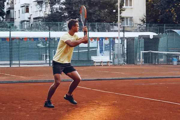 Junger schöner Mann spielt Tennis auf dem Tennisplatz — Stockfoto