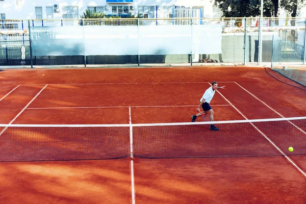 L'homme joue au tennis sur terrain de tennis en argile vue de loin — Photo
