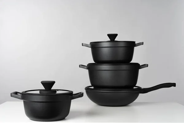 Panelas de cozinhar preto no fundo cinza vista frontal — Fotografia de Stock