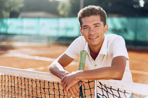 Young mixed race man tennis player with racket standing on tennis court