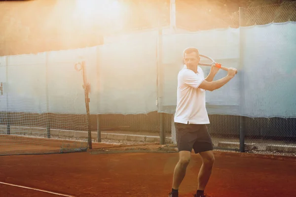 Genç adam sabahları tenis kortunda tenis oynar. — Stok fotoğraf