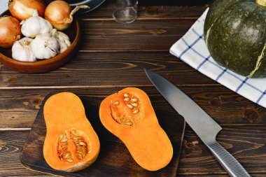 Koyu ahşap masada ikiye bölünmüş balkabağı.