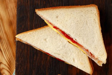 Tahta kesme tahtasında peçeteyle ikiye bölünmüş sandviçler.