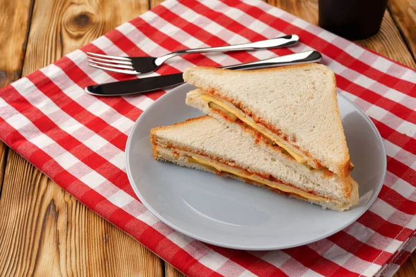 Sandwich tostado y taza de café en servilleta sobre mesa de madera — Foto de Stock
