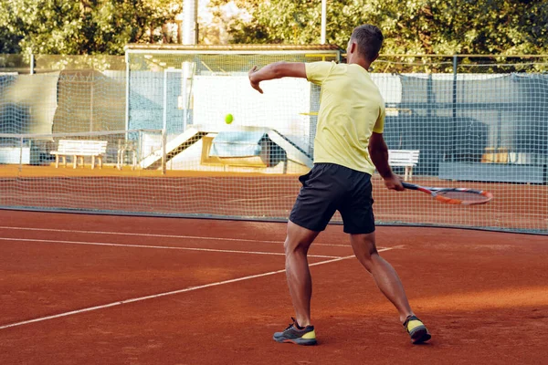 Вид сзади на человека, играющего в теннис на теннисном корте — стоковое фото