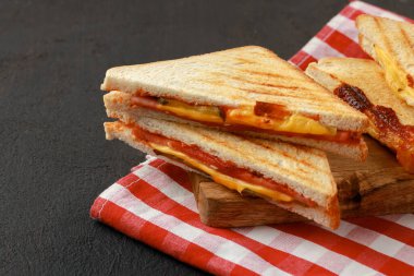 Tahta kesme tahtasında peçeteyle ikiye bölünmüş sandviçler.
