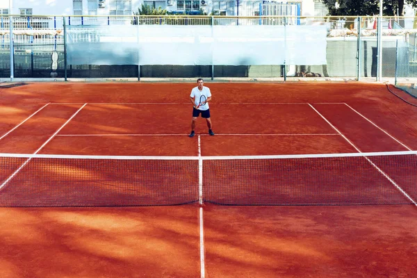 Adam uzaktan, kil tenis sahasında tenis oynuyor. — Stok fotoğraf