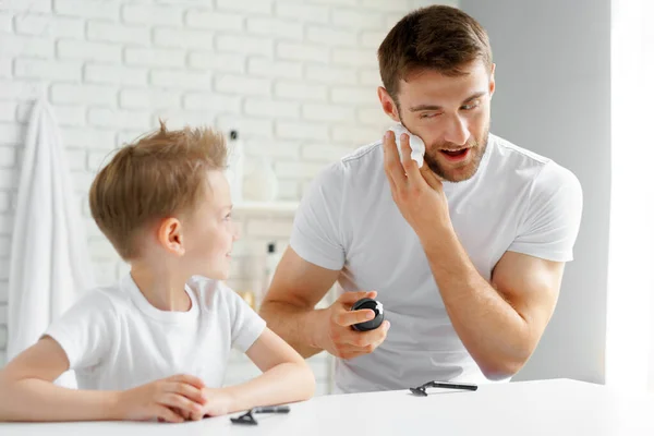 Padre enseña a su pequeño hijo a afeitarse la cara — Foto de Stock