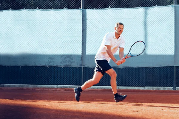 Junger Mann spielt morgens Tennis im Freien auf Tennisplatz — Stockfoto