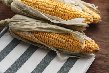 Koyu kahverengi ahşap masada mısır koçanları.