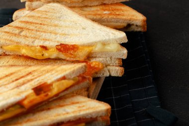 Tahta kesme tahtasında peçeteyle ikiye bölünmüş sandviçler.