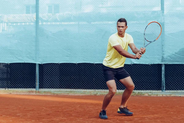 Genç yakışıklı adam tenis kortunda tenis oynuyor. — Stok fotoğraf