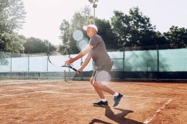 Açık havada tenis oynayan orta yaşlı bir adam dosyalanmış.