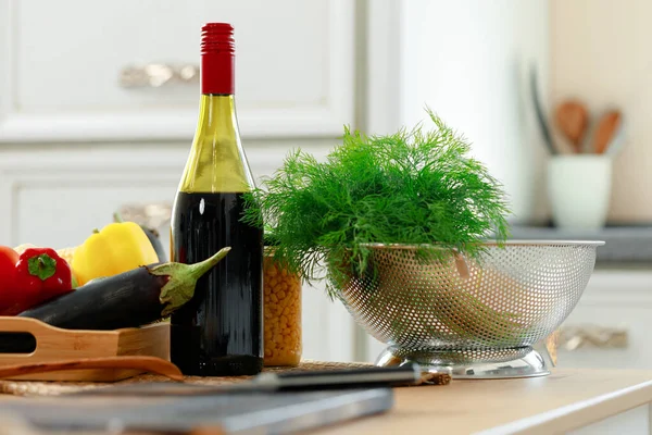 Butelka czerwonego wina i świeżych warzyw na stole kuchennym — Zdjęcie stockowe